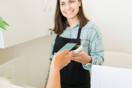 Female Beautician Receiving Payment From Customer At Spa