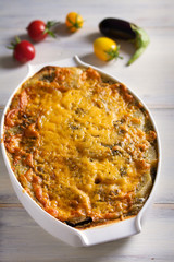 Traditional moussaka in baking dish on white wooden table