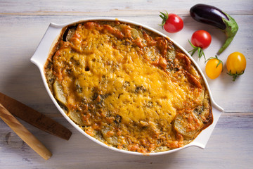 Traditional moussaka in baking dish on white wooden table. View from above, top studio shot