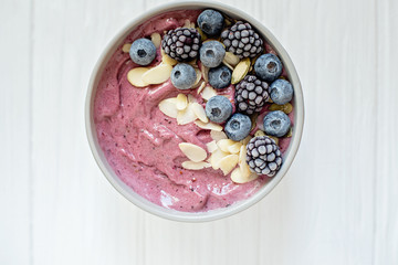 Healthy breakfast berry smoothie bowl topped with banana, granola, Blueberries and chia seeds with copy space