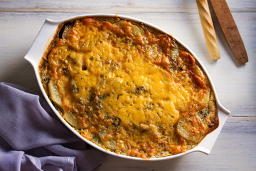 Traditional moussaka in baking dish on white wooden table. View from above, top studio shot