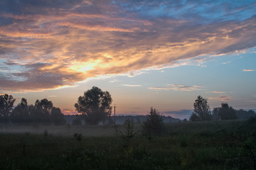 Landscape with a meadow of grass against the backdrop of a sunrise, selective focus