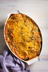 Traditional moussaka in baking dish on white wooden table. View from above, top studio shot
