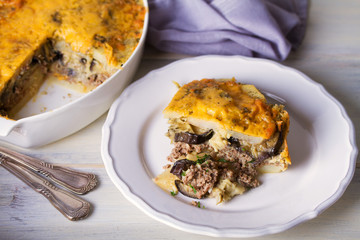 Traditional moussaka on plate and in baking dish