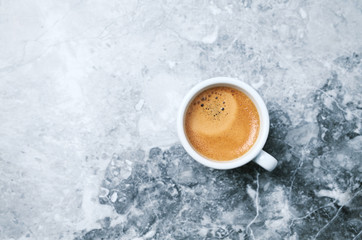 Cup of coffee on bright stone background. Top view. Copy space
