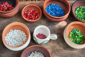 Retro mosaic cubes in clay pots. Creating patterns from processed stones. The material for decorating the walls of houses and dishes in ancient times, reconstruction.