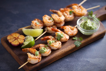 Skewered shrimps with garlic butter sauce served with cilantro and lime on serving board
