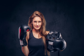 Happy smiling woman wearing boxer gloves is holding protective helmet at studio.