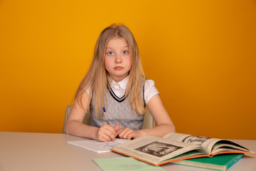 Cute and sad little girl doing homework in the bricht yellow room