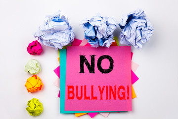 Writing text showing No Bullying written on sticky note in office with screw paper balls. Business...