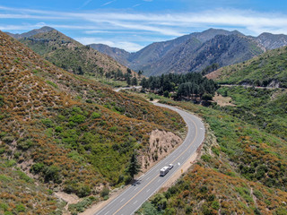 Asphalt road bends through Angeles National forests mountain, California, USA. Thin road winds between a ridge of hills and mountains at high altitude