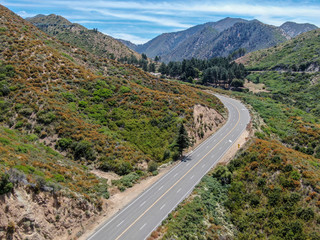 Asphalt road bends through Angeles National forests mountain, California, USA. Thin road winds between a ridge of hills and mountains at high altitude
