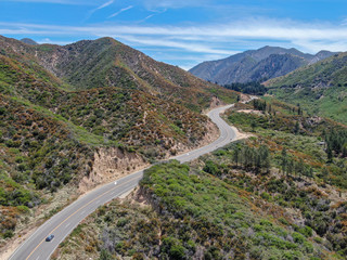 Fototapeta na wymiar Asphalt road bends through Angeles National forests mountain, California, USA. Thin road winds between a ridge of hills and mountains at high altitude