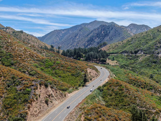 Asphalt road bends through Angeles National forests mountain, California, USA. Thin road winds between a ridge of hills and mountains at high altitude