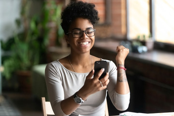 Excited black girl feel euphoric reading news on cell