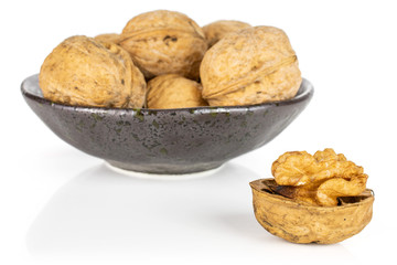 Lot of whole ripe brown walnut in dark ceramic bowl isolated on white background