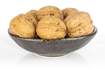 Lot of whole ripe brown walnut in dark ceramic bowl isolated on white background