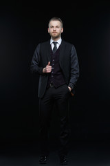 Obraz na płótnie Canvas Representative man with a beard in a three-piece suit isolated on a black background.