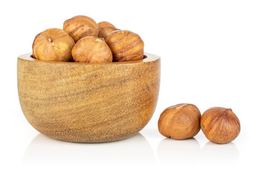 Lot of whole ripe brown hazelnut two are aside and rest is in tiny wooden bowl isolated on white background