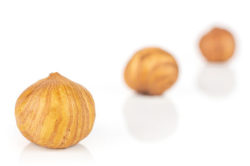 Group of three whole ripe brown hazelnut placed diagonally in line in closeup isolated on white background