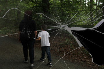 middle-aged woman in black clothes leads a child through a dark forest in a white T-shirt against...