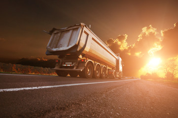 Dump truck on the countryside road against sky with sunset