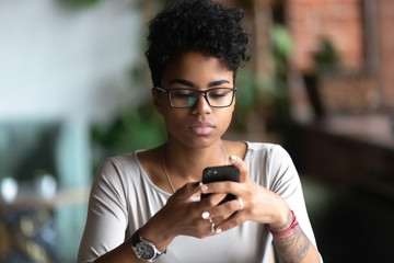 African American girl in glasses using cellphone chatting