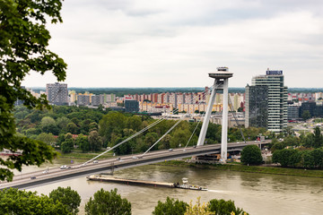 Fototapeta na wymiar Slovakia. Europe, summer 2019. River bridge. Observation deck for tourists over the city. Ship under bridge.
