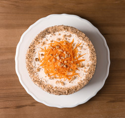 Sweet carrot cake with delicious cream on wooden table, top view