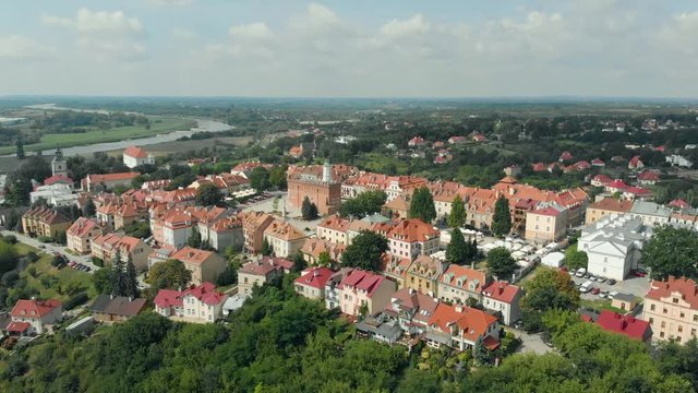 Cinematic aerial view of Sandomierz old town in Poland. Drone flying backwards and tilting up. Summer day. Sunny and clouds. Colorful green, yellow, orange red.