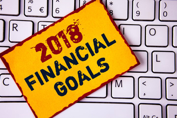 Handwriting text writing 2018 Financial Goals. Concept meaning New business strategy earn more profits less investment written Sticky note paper placed White Keyboard. Top view.