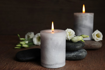 Burning candles, spa stones and flowers on wooden table