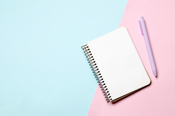 Notebook with pen on a blue and pink background. Place for text