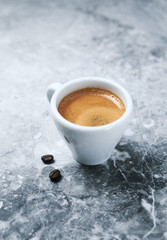 Cup of coffee and coffee beans on bright stone background. Copy space