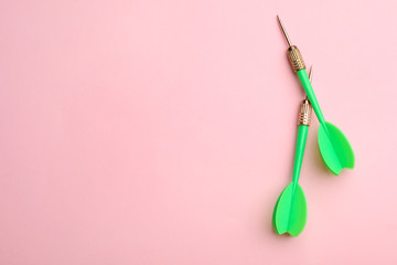 Green dart arrows on pink background, flat lay with space for text
