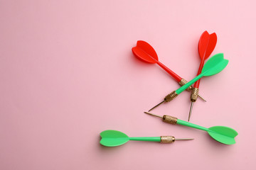Plastic dart arrows on pink background, flat lay with space for text