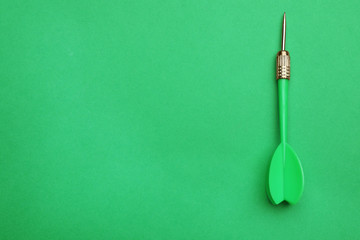 Plastic dart arrow on green background, top view with space for text