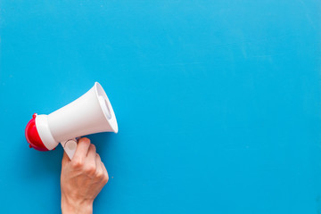 Announcement with megaphone in hand on blue background top view mockup