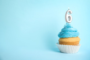 Birthday cupcake with number six candle on blue background, space for text