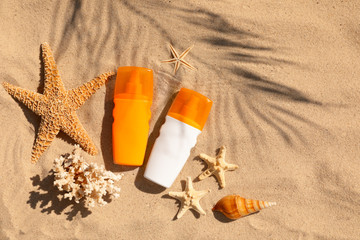 Flat lay composition with bottles of sunblock on sandy beach