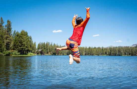Boy jumping into beautiful blue lake
