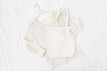 Knitted white sweater with  tote bag. Autumn/winter fashion clothes collage on white background. Top view flat lay.