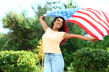 Beautiful Hispanic woman with US flag in park