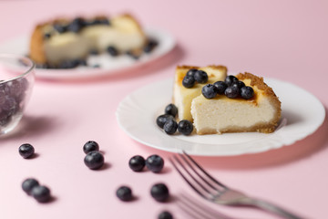 Plate with two pieces of delicious cheesecake. Pink background.