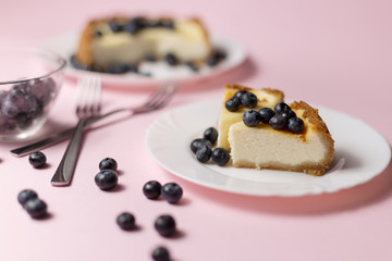 Plate with two pieces of delicious cheesecake. Pink background.