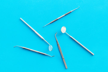 Dentist work desk with tools for teeth on blue background top view