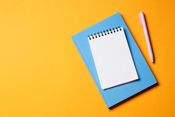 Notebook with pen on an orange background.