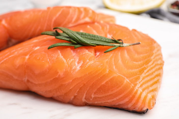 Marble board with tasty salmon fillet on table, closeup