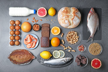 Flat lay composition with different products on dark grey background. Food allergy concept