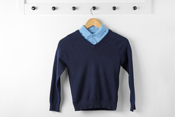 Shirt and jumper on hanger indoors. School uniform